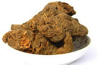 several dried herb blocks of Rehmannia Root are piled in a plate.