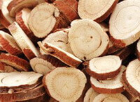 dried licorice root slices of cultivated licorice root with light reddish brown bark are piled together